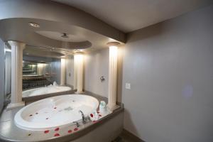 een grote badkamer met een bad en een grote spiegel bij Post Road Inn Motel in Avenel