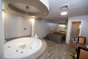a large bathroom with a tub and a bedroom at Post Road Inn Motel in Avenel