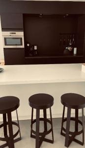 uma cozinha com três bancos de bar pretos num balcão em Dolce Vita - zonnig familie appartement met garagebox em Nieuwpoort