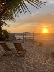 einen Strand mit zwei Stühlen und einer Schaukel bei Sonnenuntergang in der Unterkunft Casa Kayab in Puerto Morelos