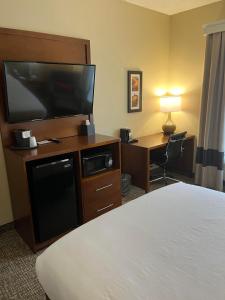 a hotel room with a bed and a television and a desk at Wingate by Wyndham West Mifflin in West Mifflin