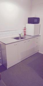 a white kitchen with a sink and a microwave at Modest comfortable relaxed home away from home in Rotorua