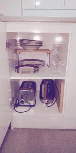 einen Küchenschrank mit Geschirr und Tellern sowie einem Toaster in der Unterkunft Modest comfortable relaxed home away from home in Rotorua