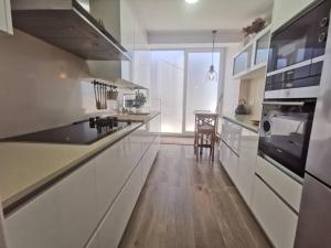 eine große Küche mit weißen Schränken und einem Tisch in der Unterkunft Tomás Paredes, Vigo, 3 habitaciones in Vigo