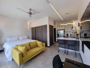 ein Schlafzimmer mit einem Bett und einem gelben Sofa sowie eine Küche in der Unterkunft Loft conveniently located five minutes from airport in San José