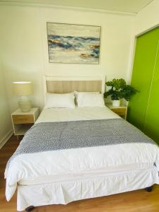 a bedroom with a white bed with a green wall at The Waves, 806 Quayside Point Waterfront in Durban