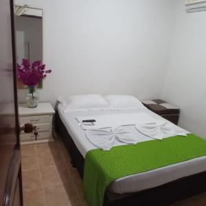 1 dormitorio con 1 cama y un jarrón de flores en Hostal Villa del Río Las Brisas, en Villavieja