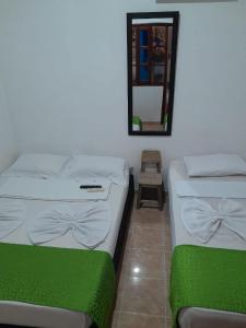 2 camas en una habitación con espejo y silla en Hostal Villa del Río Las Brisas en Villavieja