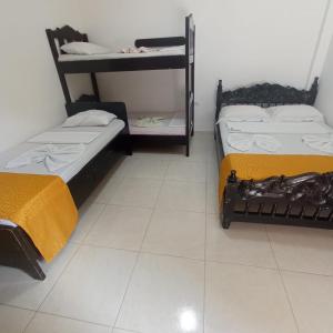 two beds in a room with a white tile floor at Hostal Villa del Río Las Brisas in Villavieja