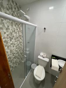 a bathroom with a toilet and a glass shower at Hotel Cajueiro Guarujá in Guarujá