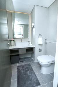 een badkamer met een toilet, een wastafel en een spiegel bij DAMAC MAISON PRIVE in Dubai