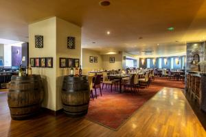 un restaurant avec des tables en bois, des chaises et des tonneaux dans l'établissement Gloucester Robinswood Hotel, BW Signature Collection, à Gloucester