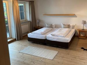 a bedroom with a large bed with white sheets and pillows at Chalet Jochpass Ferienwohnungen by HOTEL LANIG - Ferienwohnungen mit Zugang zum WellnessSpa im Hotel Lanig in Bad Hindelang