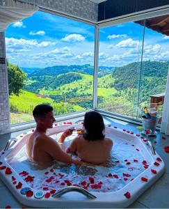 un hombre y una mujer en una bañera con vistas en Pousada Colina das Andorinhas en Gonçalves
