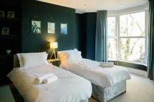 Cette chambre comprend 2 lits dans une chambre dotée de murs bleus et d'une fenêtre. dans l'établissement Luxurious 4 bedroom townhouse in Buxton, à Buxton