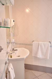 a white bathroom with a sink and towels at Villa Margherita in Naples