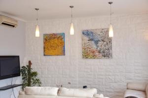 uma sala de estar com um sofá e pinturas na parede em Villa Margherita em Nápoles