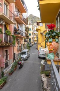 una strada cittadina con auto parcheggiate sul lato di un edificio di Amunì Taormina a Taormina