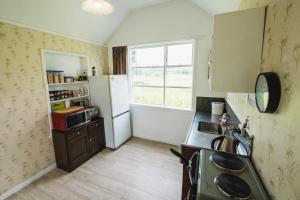 a small kitchen with a refrigerator and a window at Cliff Top Cottage 