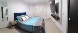 1 dormitorio pequeño con 1 cama y TV en Cómodo dpto full equipo 2 hab, seguridad y parqueo privado, en Guayaquil