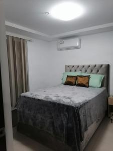 1 dormitorio con 1 cama grande en una habitación blanca en Cómodo dpto full equipo 2 hab, seguridad y parqueo privado, en Guayaquil