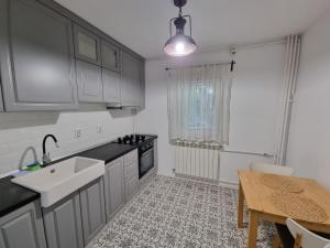 een keuken met witte kasten, een wastafel en een tafel bij Aviatiei Apartments near Caramfil street in Boekarest