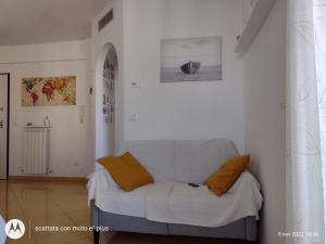 uma sala de estar com um sofá branco com almofadas laranja em Appartamento Torri di Avvistamento em Porto Recanati