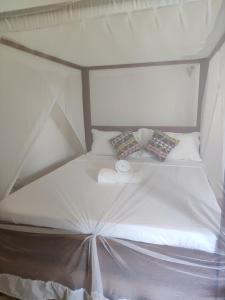Una cama blanca con dos almohadas encima. en MaNa Nungwi en Nungwi