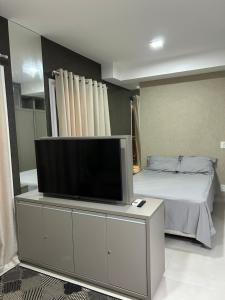 uma televisão numa cómoda num quarto com uma cama em Flat Duo JK. Lindo e completo em São José do Rio Preto
