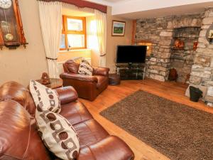 a living room with leather furniture and a stone fireplace at Pant Teg Farm in Kidwelly