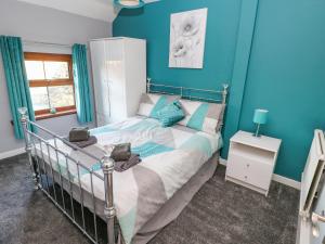 a bedroom with a bed with blue walls at Pant Teg Farm in Kidwelly