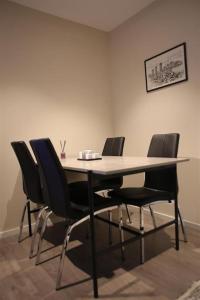a table with four chairs in a room at Sentral leilighet med 3 soverom in Harstad