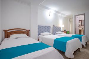 three beds in a room with white and blue at Hotel Ayenda Boutique Real Capital Monteria in Montería