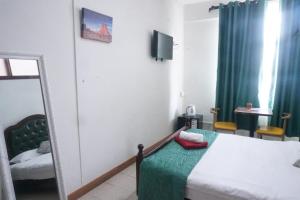 a small bedroom with a bed and a mirror at Happy Ours Guesthouse in Curepipe