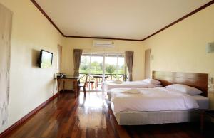 a bedroom with two beds and a table with chairs at Be Fine Sabuy Hotel and Resort in Surat Thani