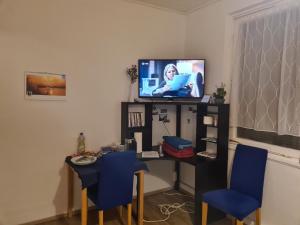 Habitación con escritorio, TV y sillas azules. en Charmantes helles Zimmer zentrumnah und naturnah en Göppingen