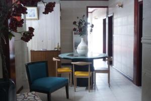 Happy Ours Guesthouse في Curepipe: طاولة وكراسي في غرفة عليها مزهرية