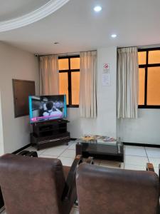 sala de estar con 2 sillas y TV de pantalla plana en Inter Hotel, en Vitória