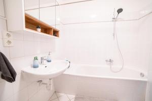 a white bathroom with a sink and a bath tub at FULL HOUSE Premium Apartments Magdeburg E3 in Magdeburg