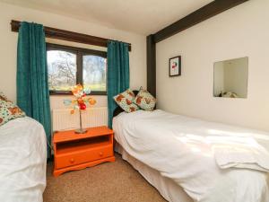1 dormitorio con 2 camas y ventana en Bracken Cottage, en Okehampton