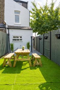 a wooden picnic table in a yard next to a fence at Stunning and spacious house, with Free Parking and huge Garden, 5 Min to metro in London