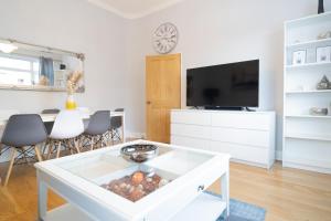 ein Wohnzimmer mit einem Tisch und einem TV in der Unterkunft Stunning and spacious house, with Free Parking and huge Garden, 5 Min to metro in London