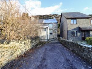 a stone house with a stone wall and a driveway at 1 Llwyn Hir in Blaenau-Ffestiniog