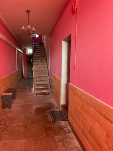 un couloir vide avec un mur rouge et des escaliers dans l'établissement La Manufacture Royale de Bains, à Bains-les-Bains