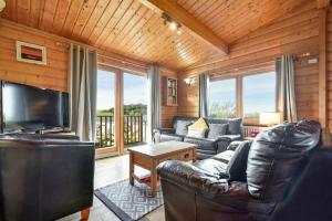 a living room with a leather couch and a television at Heather Cottages - Grey Heron in Bamburgh