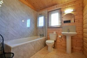 a bathroom with a toilet and a tub and a sink at Heather Cottages - Grey Heron in Bamburgh +15 photos