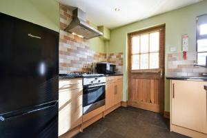 een keuken met een zwarte koelkast en een fornuis bij Heather Cottages - Godwit in Bamburgh