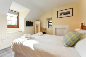 a bedroom with a large white bed with towels on it at Heather Cottages - Godwit in Bamburgh