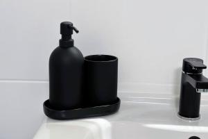 a black soap bottle and a cup on a sink at City-Apartment in Krefeld - BEUYS Apartments - Krefeld in Krefeld