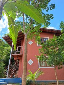 una casa rossa con un albero di fronte di Suite Solteiro Cristal Rosa, Suites Ananda a Alto Paraíso de Goiás
